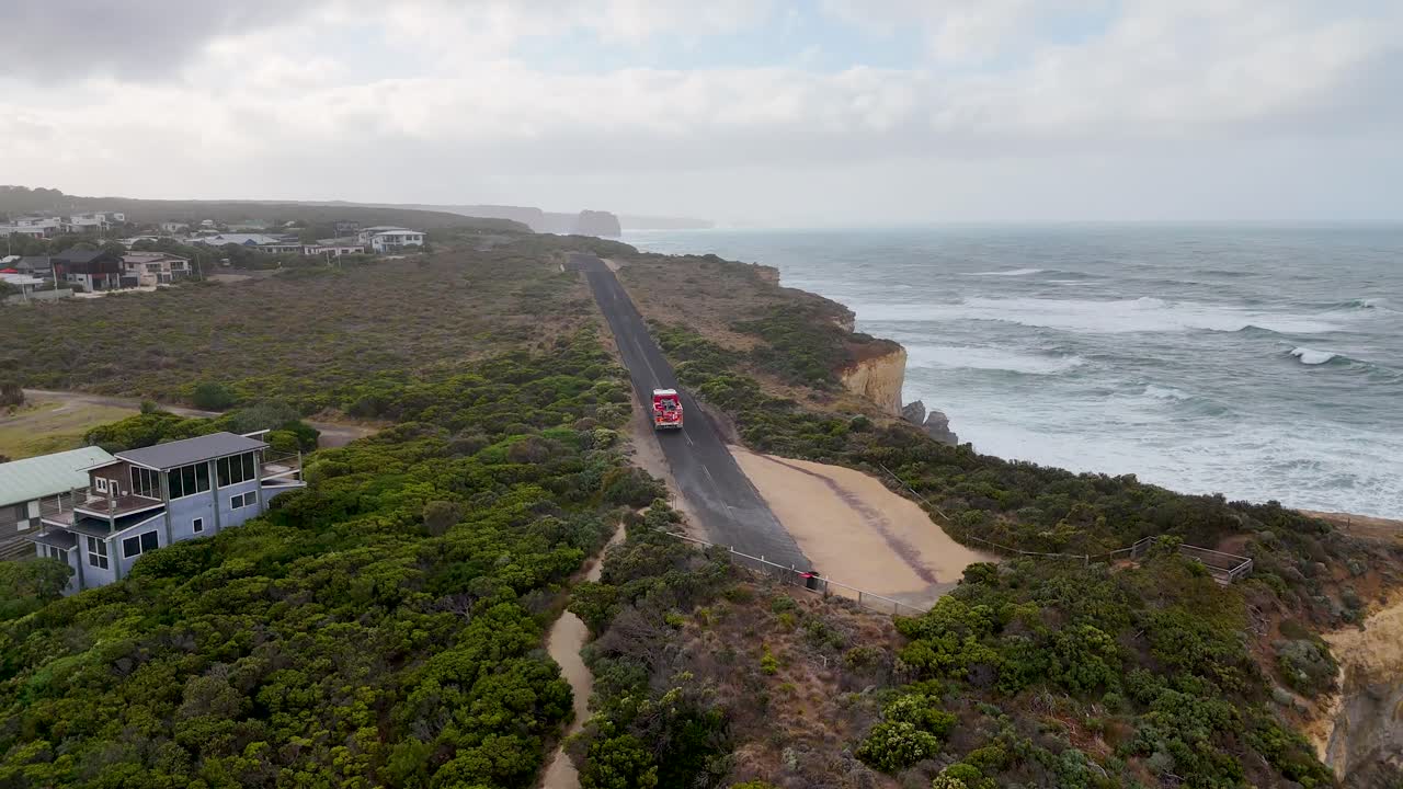 Drone captures a fire engine traveling along a scenic coastal road in Port Campbell, Australia, with dramatic ocean views