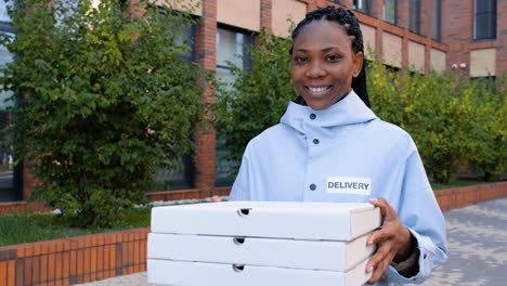 mujer joven sosteniendo cajas de pizza