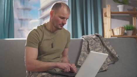 a professional military man sits on a sofa with a living room at home and uses a notebook close up