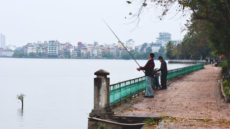 two people fishing by a scenic pond