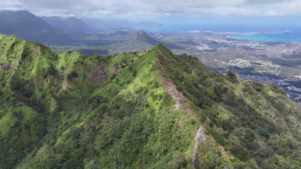 Drone aerial view of Oahu, Hawaii, over lush mountains dense forest, and vibrant landscapes with sea ocean water at distance