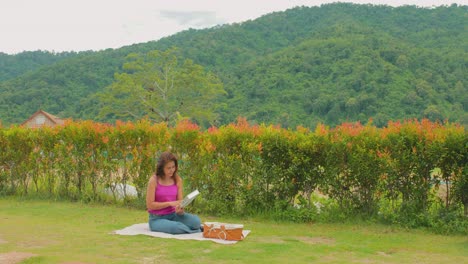 Ruhiges-Gartenpicknick-Mit-Einer-Thailändischen-Frau,-Die-Ein-Buch-Liest,-Inmitten-Atemberaubender-Aussicht-Auf-Die-Hügel