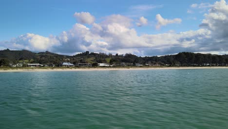 Cinematic-drone-shot-of-beachside-town-with-holiday-bach-in-New-Zealand