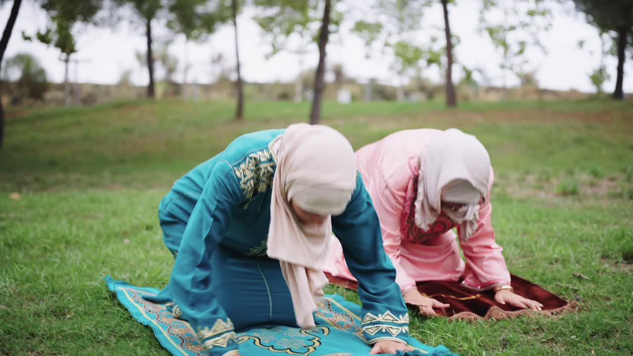 Two Muslim women praying outdoors
