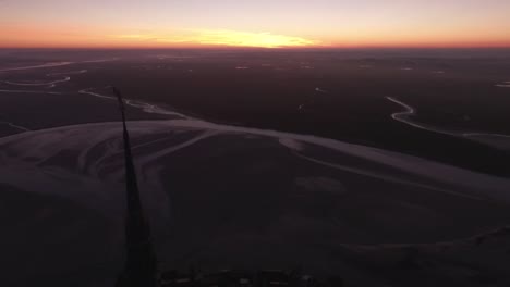 Silhouette-of-spire-of-Mont-Saint-Michel-abbey-at-twilight-with-bay-in-background,-Normandy-in-France