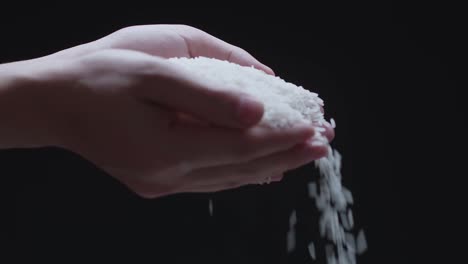 raw white rice falling from hands in a slow motion