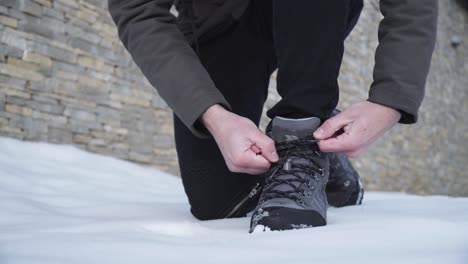 Close-up-of-a-hiker-tying-his-boots-in-snow-and-walking-away