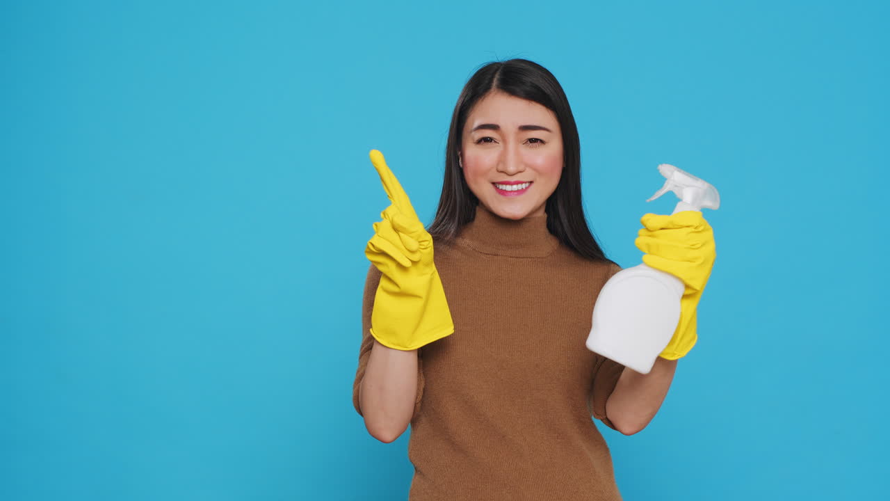 Asian housekepper pointing and showing hygiene products or isolated text