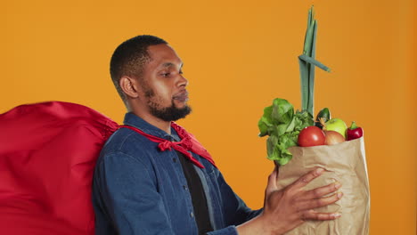 african american guy posing as a superhero with fresh ripe produce