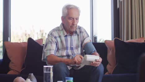 Video-of-focused-caucasian-senior-man-checking-pressure