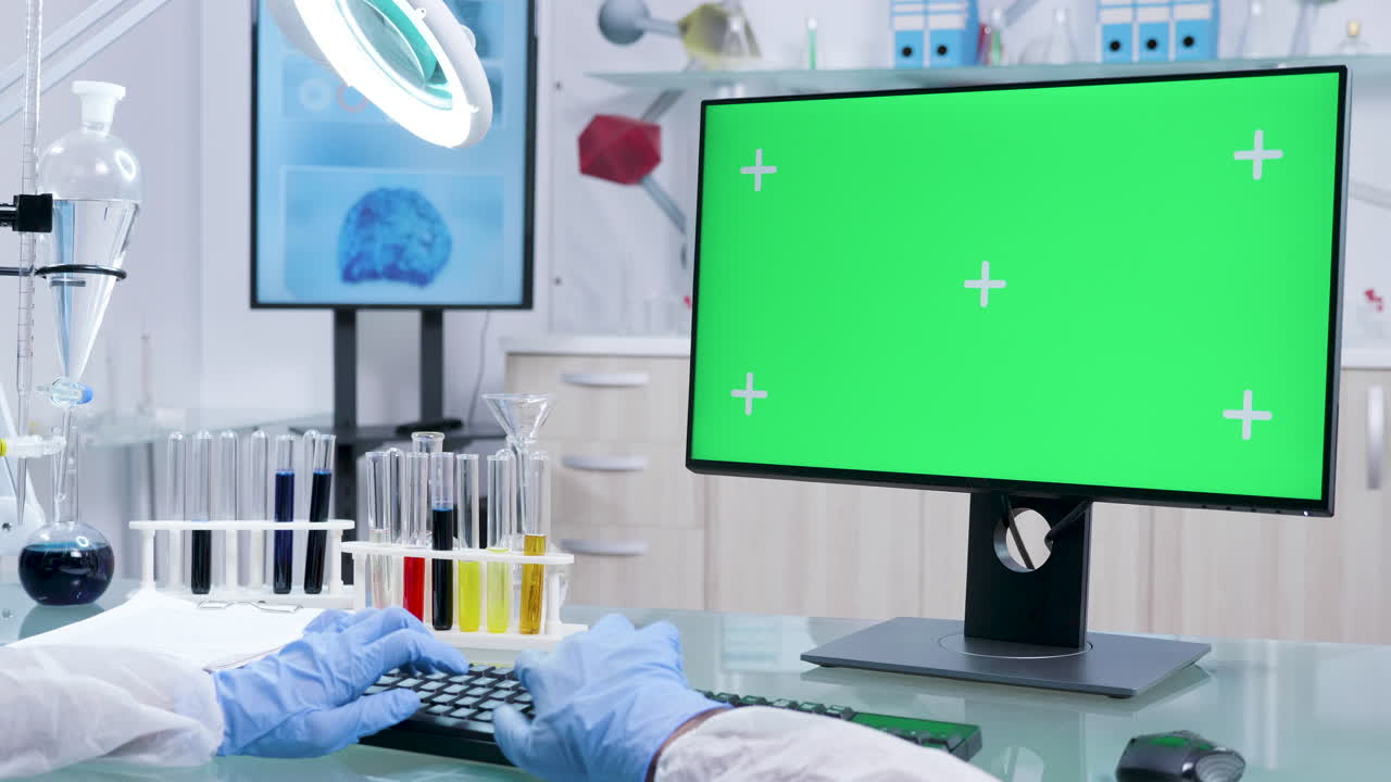 Scientist working in a lab with a computer with a green screen