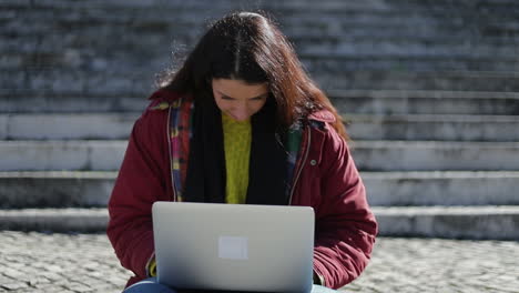 mujer concentrada con cabello largo escribiendo en una computadora portátil