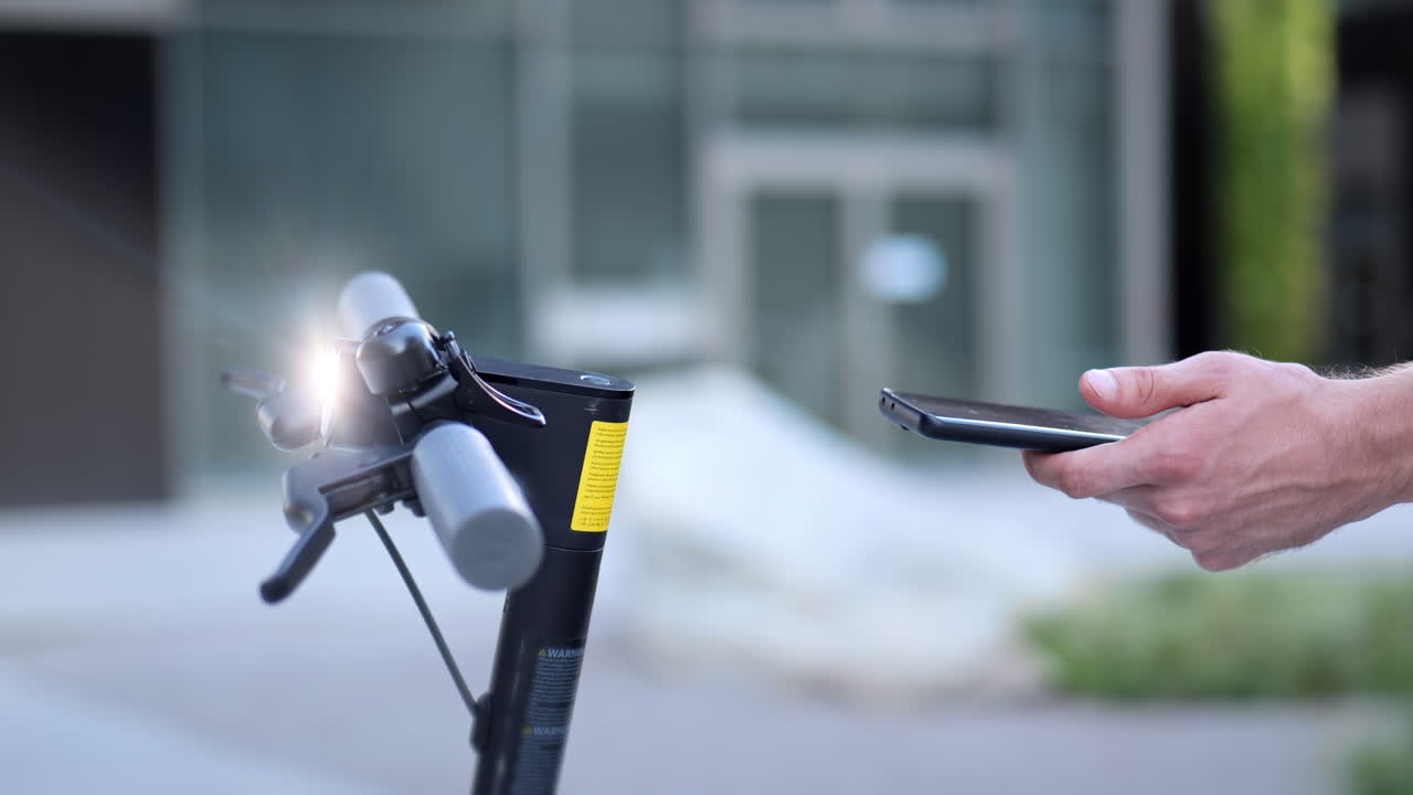 mano de un joven desbloquear y encender scooter electrónico con aplicación de teléfono inteligente en el dispositivo móvil