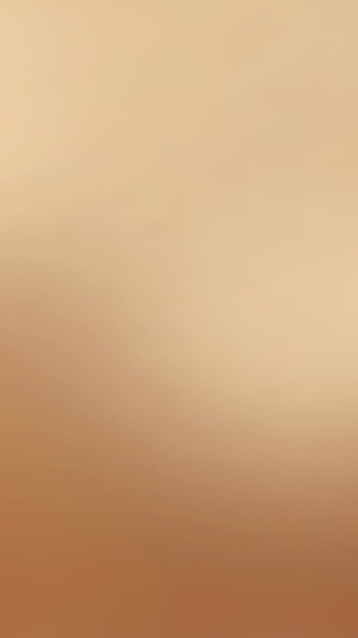 Vertical video: Autofocus causing camera lens shifting focus at studio closeup, soft beige gradient