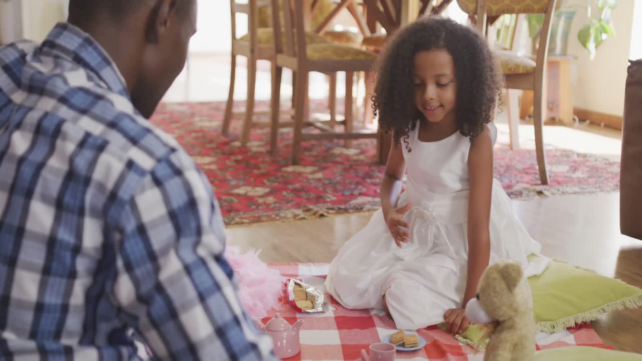 Padre e figlia afroamericani che fanno un picnic a casa