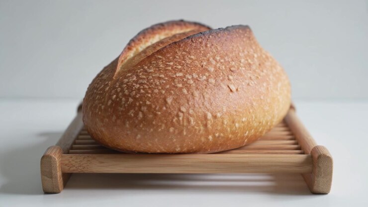 Camera moving closer to round artisan loaf on wooden rack at kitchen counter, showing crust texture