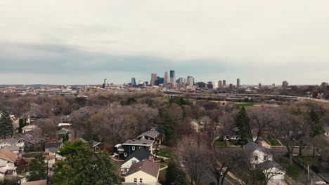 Eine-Breite-Luftaufnahme-Einer-Drohne-Von-Der-Skyline-Von-Minneapolis-In-Minnesota-An-Einem-Frühlingstag-Mit-Vorstadthäusern-Im-Vordergrund,-Die-Baseballfelder-Und-Eine-Stadtautobahn-Zeigen