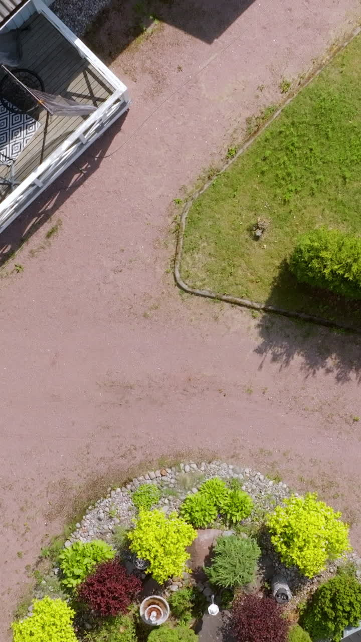 Vertical aerial above a blooming summer garden and solar panels on a house roof