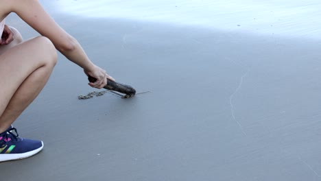 person creating patterns on beach with wood