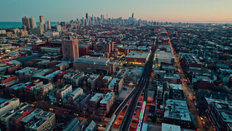 Siguiendo-El-Tren-De-Vacaciones-Cta-Decorado-Con-Navidad-En-El-Ferrocarril-Brown-Lane-E-Inclinándose-Hacia-Arriba-Con-Una-Vista-épica-Del-Horizonte-De-Chicago-Al-Atardecer-4k