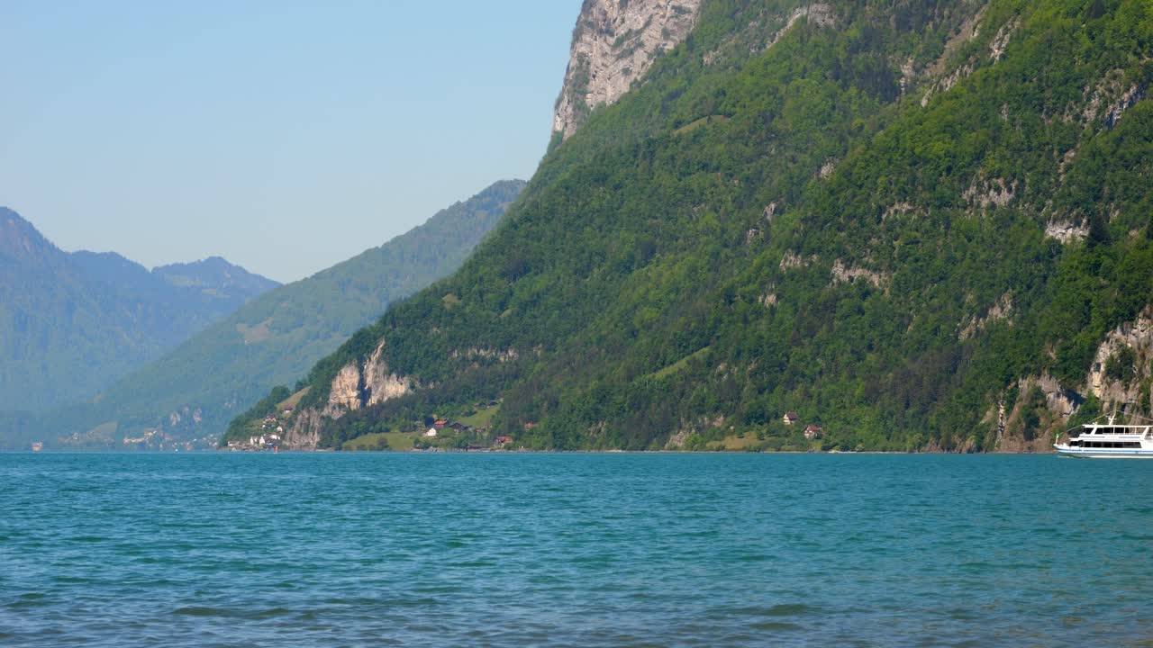 A tourist boat sails on Lake Walensee in spring. You can see the beautiful natural landscape with the mountains. Everything is blooming and colorful.