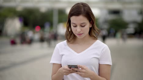 Vista-Frontal-De-Una-Mujer-Tranquila-Enviando-Mensajes-De-Texto-Durante-El-Paseo.