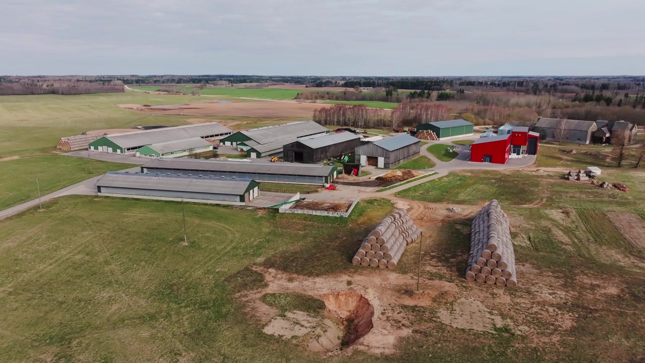Moderne lettisk gård set ovenfra med lader, marker og stablede ensilageballer
