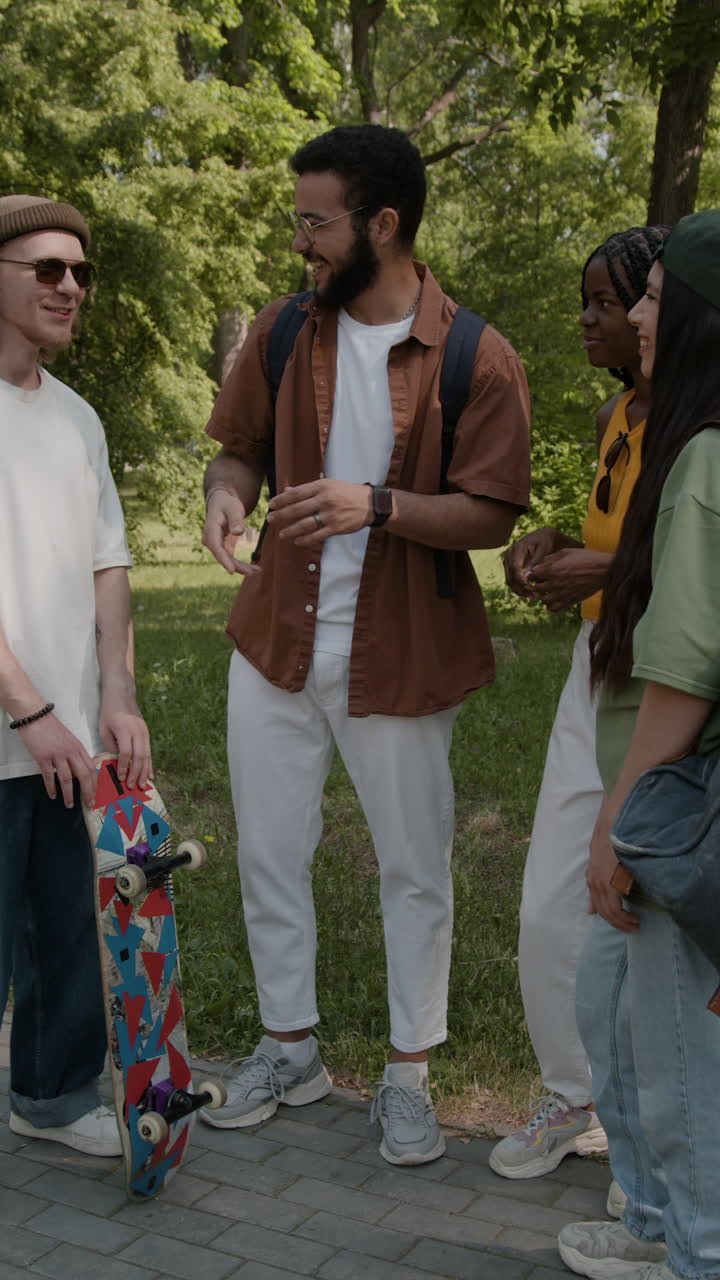 A diverse group of friends conversing in a park with a skateboard