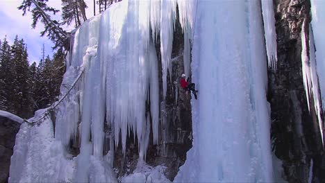 an extreme wide shot of a man climbing a frozen waterfall