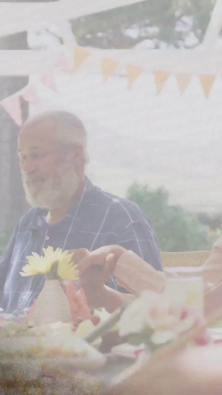 Vertikales Video: Älterer Mann bekommt Blume, funkelnde AR-Symbole über Tellern, während Familie Essen teilt