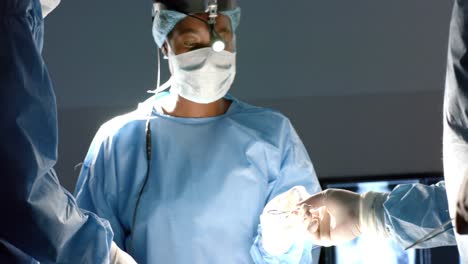 Diverse-surgeons-wearing-surgical-gowns-operating-on-patient-in-operating-theatre,-slow-motion