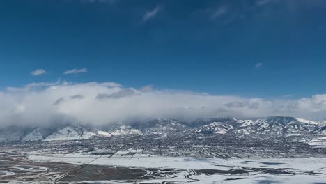 在一個令人驚訝的雪山谷上空的陡峭的飛行,遠處有山和雲