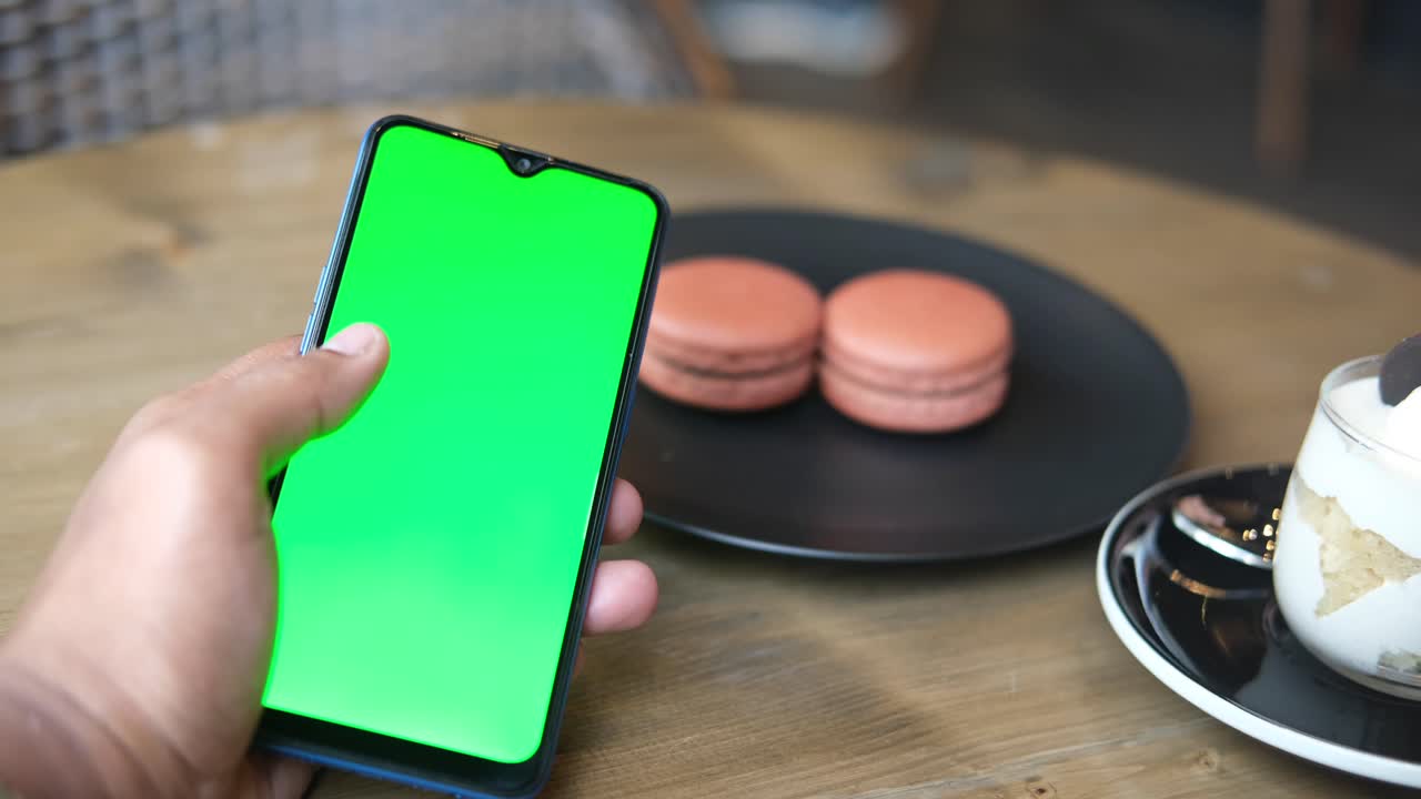 persona usando un teléfono de pantalla verde en un café
