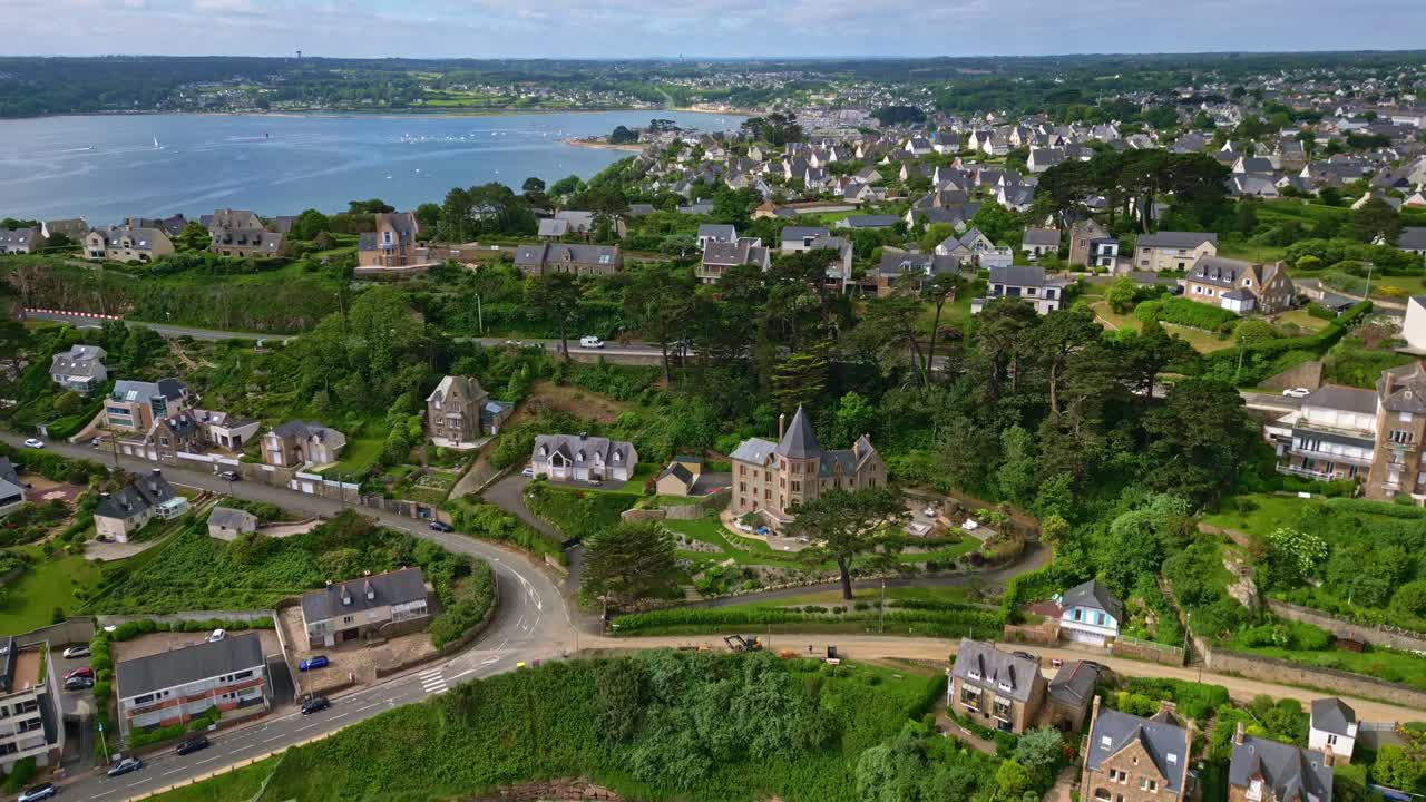 Bird's eye drone view over the French Trestrignel beach with spread-out beautiful houses and green environment, Perros-Guirec, Brittany, France.