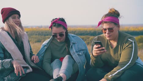 girl hikers with smartphone and thermos on green meadow