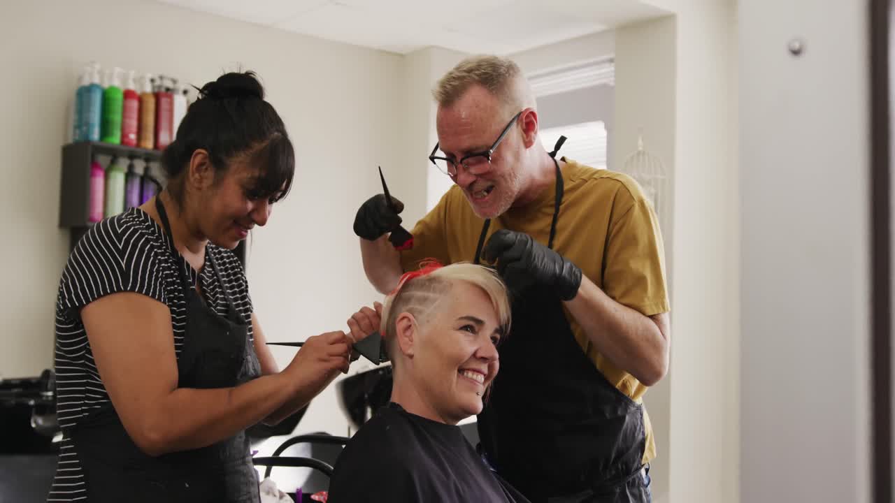 Zijaanzicht van een vrouw die haar haar laat stylen door twee kappers