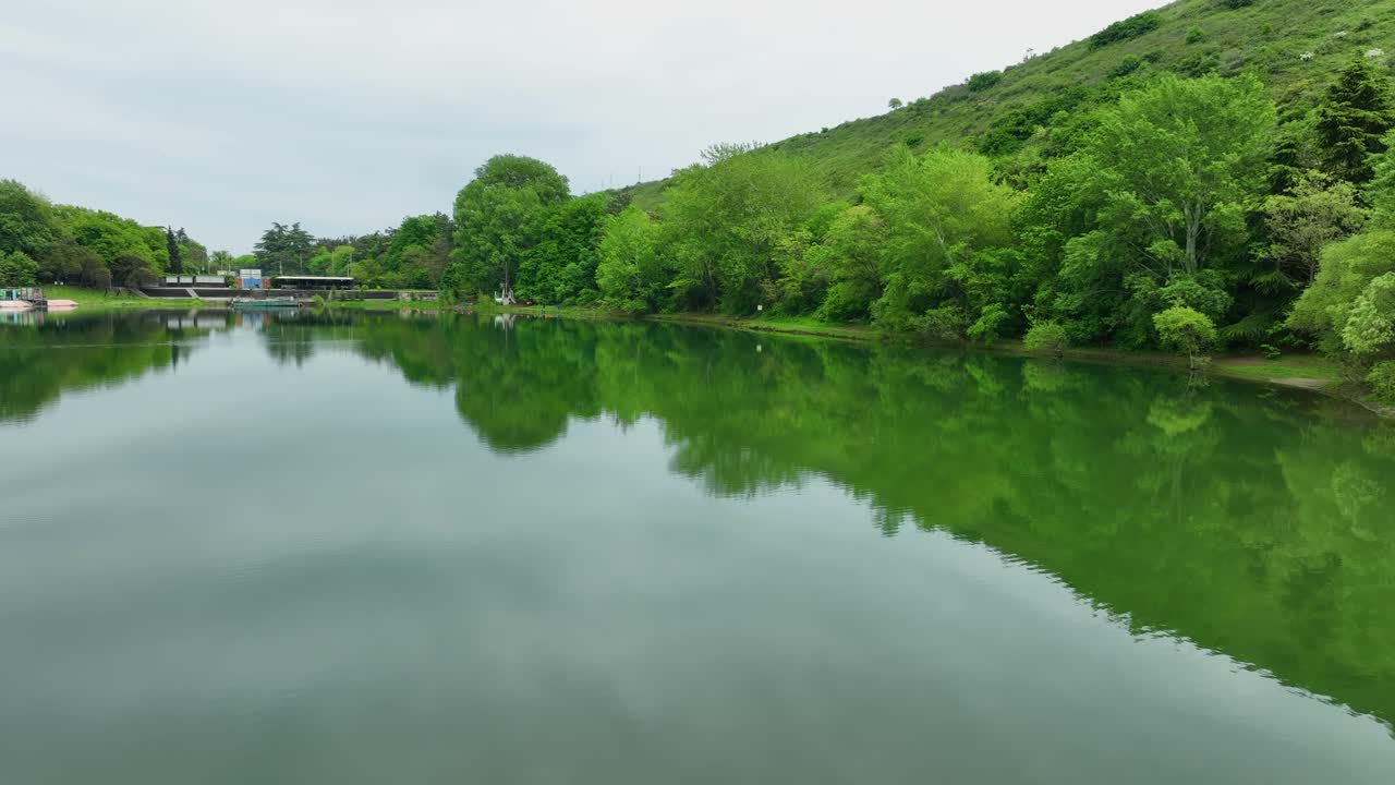 Tranquil lake scene with vivid green trees reflecting on still water, showing the pure natural beauty of the area