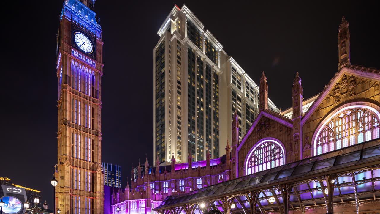 Torre do relógio da cidade e arquitetura iluminadas com cores em constante mudança à noite.