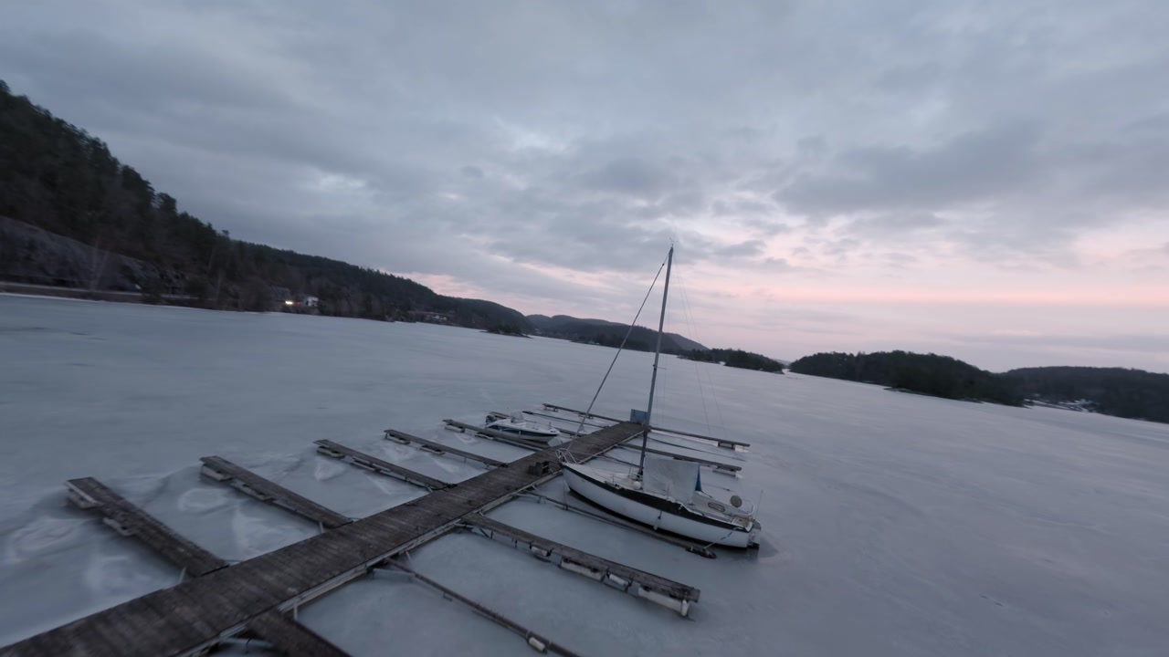 Wooden dock and sailboat on frozen Norwegian fjord landscape