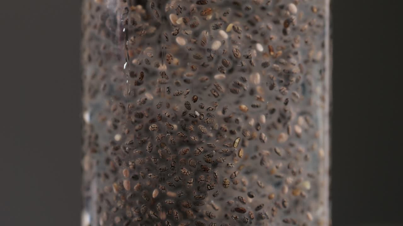 Chia seeds blending and rotating in water close-up macro black background. Dry healthy ingredient. Healthy superfood rich in Omega 3 fatty acids. Salvia hispanica
