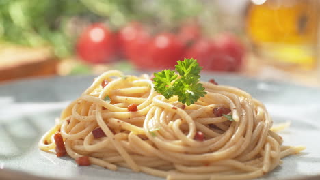 decorar el espagueti carbonara con perejil - plato de vapor recién preparado en un plato brillante en la cocina, dolly out, cámara lenta