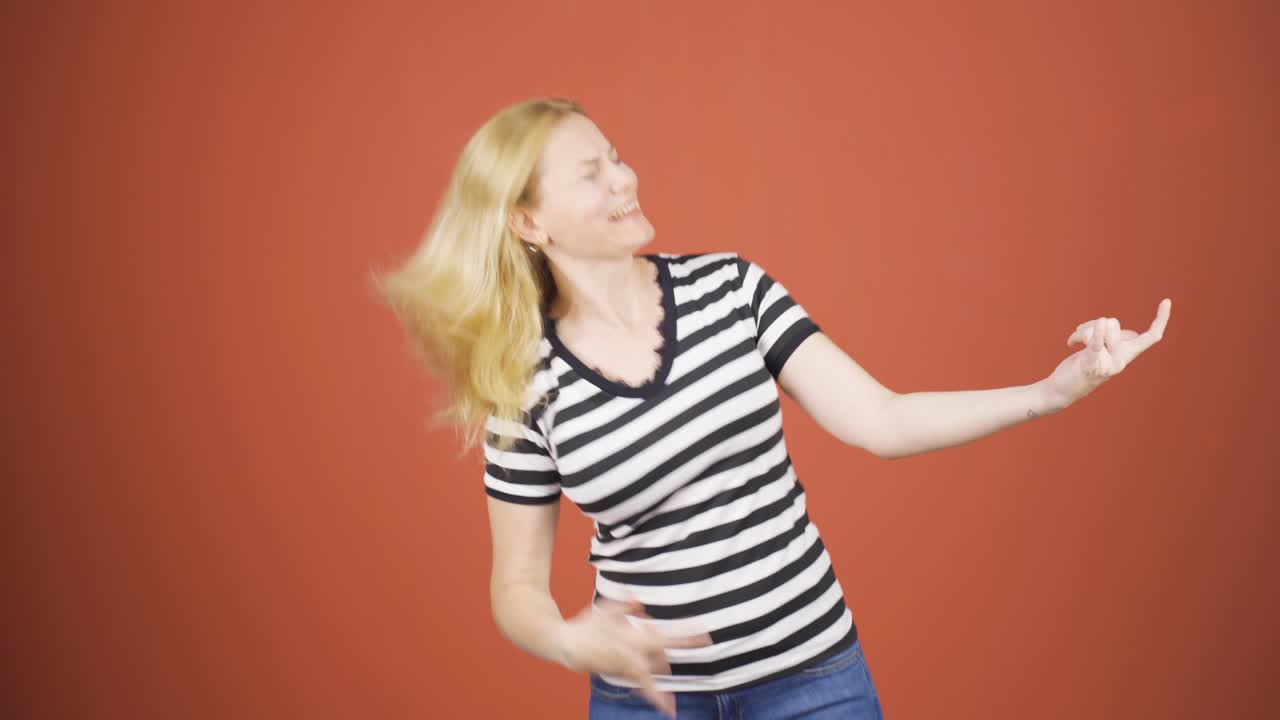 mujer haciendo señas de rocker y bailando.