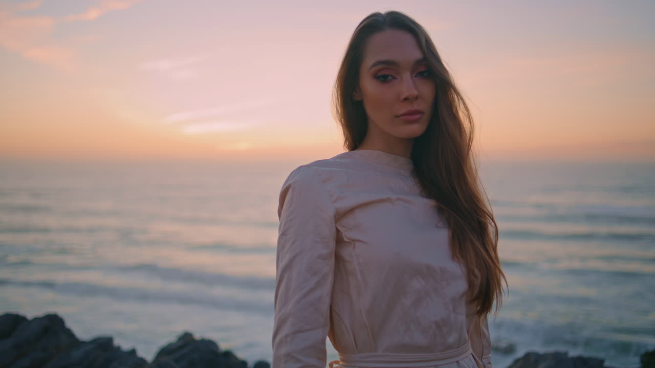 viaje chica caminando colina de la noche en la vista del océano. mujer serena mirando cámara