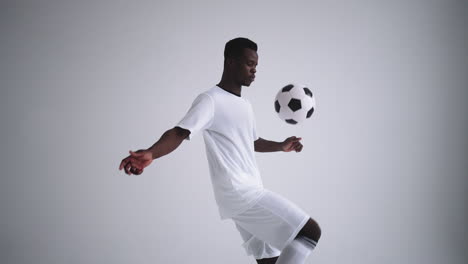 slow motion: one african man soccer player white jersey juggling in silhouette on white background. one black brazilian soccer football player man silhouette