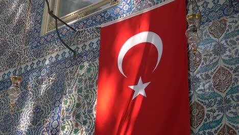 turkish flag hanging on a building with iznik tiles