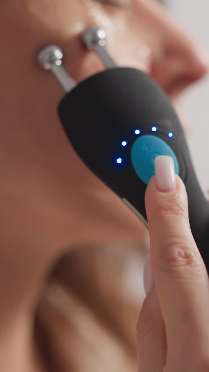 la mujer utiliza un dispositivo de microcorrientes con efecto curativo en la piel. la mujer con manicura hace un procedimiento de microcorrentes para brillar la piel en la ducha en cámara lenta