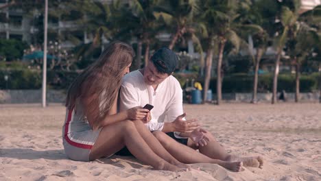 people sit on yellow sand and long haired brunette texts