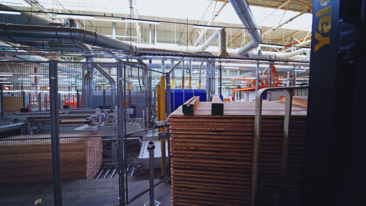 Interior of factory for wooden production. Wooden boards for floor parquet inside the huge industrial plant. Piles of plywood in the manufacturing.