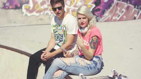 young couple of skateboarders sitting chatting