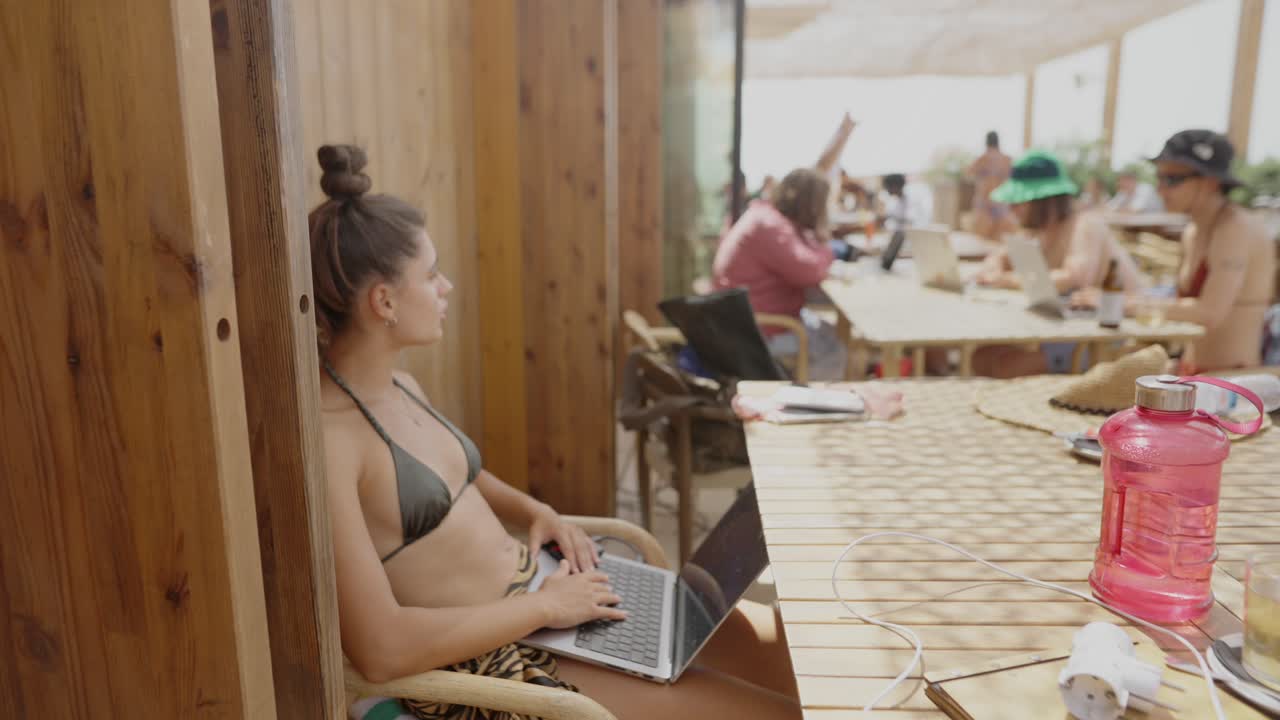 Woman working on laptop at beach cafe